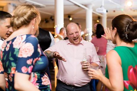 Wedding guest dancing whilst holding a beer. 