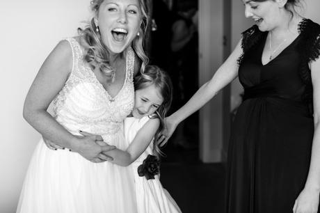 Bride smiles and hugs bridesmaid at Asylum wedding. 