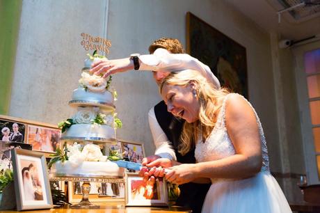 Groom hold cake from falling down at London wedding during cake cutting. 