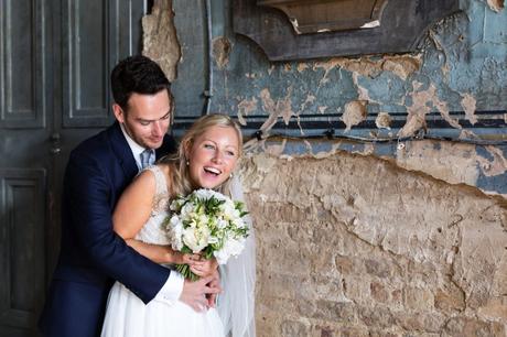 Bride and groom laugh next to de-constructed wall at the Asylum in London