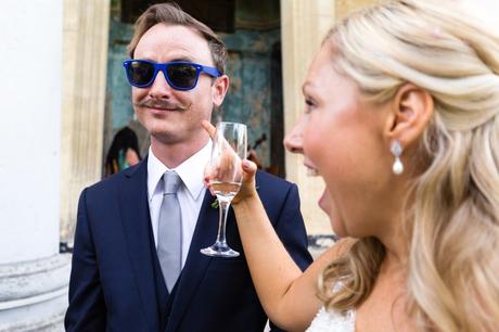 Bride points at groomsman's handlebar moustache whilst he wears sunglasses at Asylum wedding. 