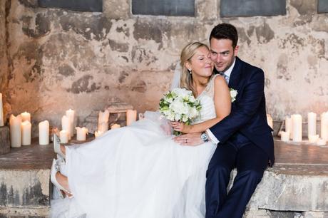 Bride and groom snuggle in front of candles at Asylum wedding. 