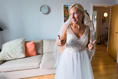 Bride gives thumbs up in beaded wedding dress. 
