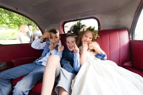 Little kids sitting in back of vintage car at wedding making thumbs up at Asylum wedding. 