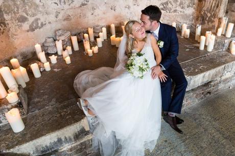 Top-down shot of groom kissing bride encircled in candles at The Asylum wedding. 