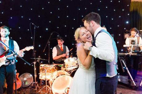 Groom kisses bride on cheek at London wedding. 