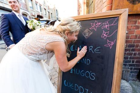 Bride rubs out wrong letter on chalkboard at her wedding. 