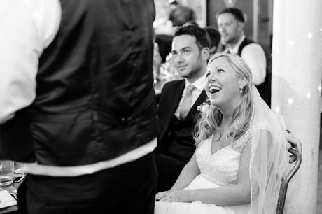 Bride smiles at dad during wedding speeches. 