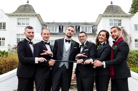 Groom makes silly face with cane with wedding party
