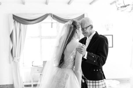 Wedding photograph of bride's father presses his forehead into bride's face as he sees her for the first time. 