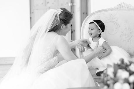 Bride having a sweet moment with little flower girl who is sticking out her tongue. 
