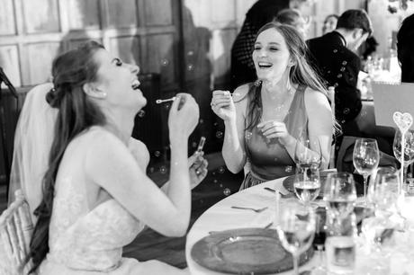 Bride and sister laughing whilst blowing bubbles at Achnagairn Estate wedding. 