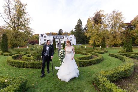 Bride and groom walk through autumn garden maze at Achnagairn Estate