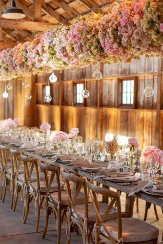 wedding trends 2019 long table in barn with suspended flowers and glass decor eddiezaratsian