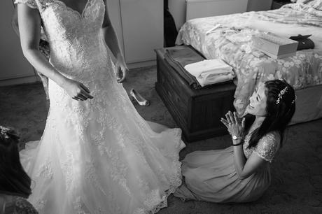 a bridesmaid helps the bride with her dress