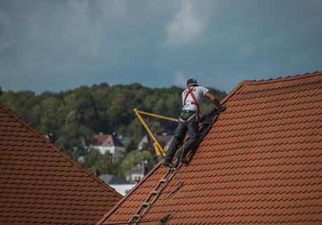 roofer on a roof checking tiles.