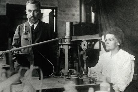 Image: Pierre and Marie Curie in the laboratory, demonstrating the experimental apparatus used to detect the ionisation of air, and hence the radioactivity, of samples of purified ore which enabled their discovery of radium | c:a 1904 | Wikipedia