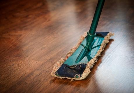 A mop resting on a brown wooden floor.