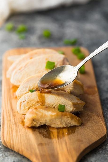 spooning the thickened honey garlic chicken marinade over a sliced chicken breast