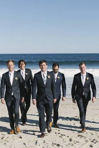 groomsmen photos groom and groomsmen walking on beach