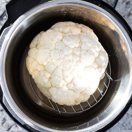 overhead view of a whole head of cauliflower in an instant pot