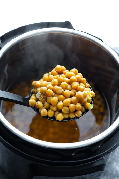 spoon scooping cooked chickpeas out of an instant pot