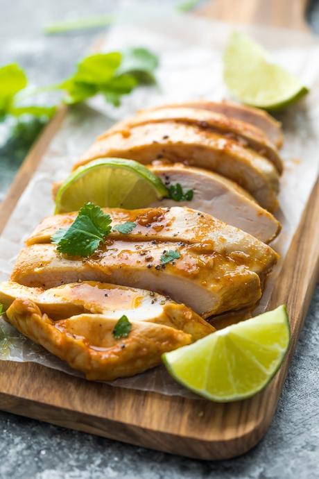 Chipotle chicken sliced on cutting board with lime wedges