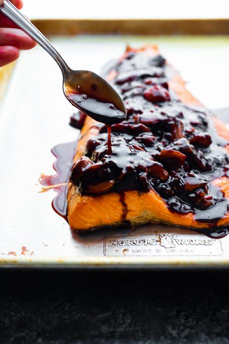 spooning strawberry balsamic sauce over salmon