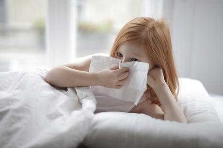 sick-little-girl-blowing-nose-with-tissue-lying-in-bed-3887616