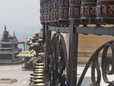 The prayer wheels and oil candles surrounding the large stupa