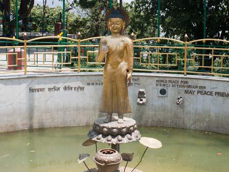 A standing Buddha statue at the base of the hill