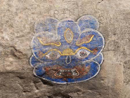 A monkey mask painting on a stone leading to the temple