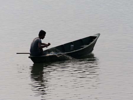 A man with a fishing net on Lake Phewa Tal