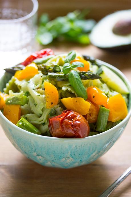 side angle view of avocado pesto pasta salad in a bowl