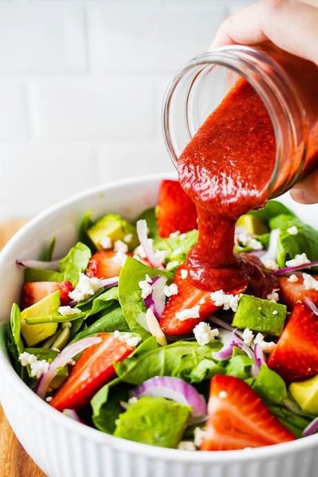 pouring vinaigrette over strawberry spinach salad