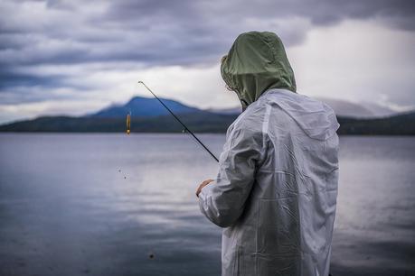 person with fishing rod in rain suit