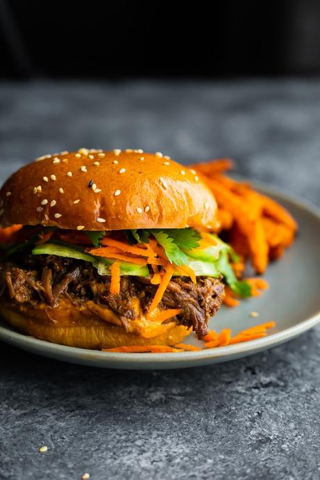 honey garlic shredded beef sandwich on a plate with sweet potato fries