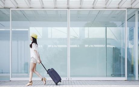 Woman-with-a-hat-and-a-hardside-luggage-in-her-hand