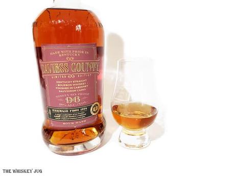 Davies County Bourbon Cabernet Sauvignon Finish bottle with a white background and tasting glass of whiskey next to it.