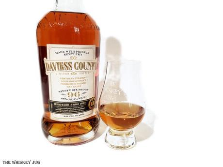 Daviess County Bourbon French Oak Finish bottle with a white background and tasting glass of whiskey next to it.