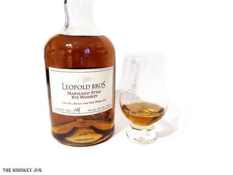 White background tasting shot with the Leopold Bros. Maryland Style Rye Whiskey bottle and a glass of whiskey next to it.