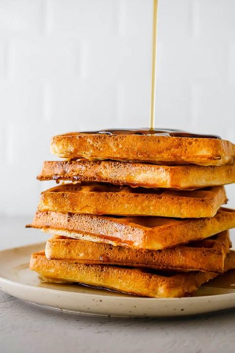 syrup drizzling on a stack of yeast waffles