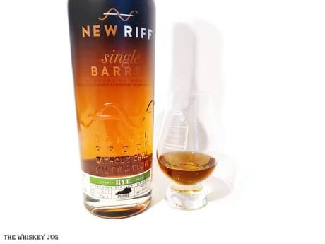 White background tasting shot with the New Riff Single Barrel Rye bottle and a glass of whiskey next to it.
