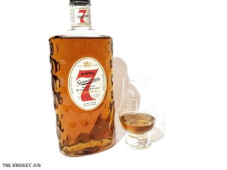 White background tasting shot with the Seagram's 7 Crown American Blended Whiskey bottle and a glass of whiskey next to it.