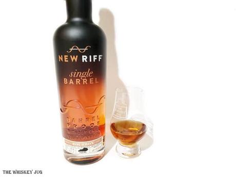 White background tasting shot with the New Riff Single Barrel Bourbon bottle and a glass of whiskey next to it.