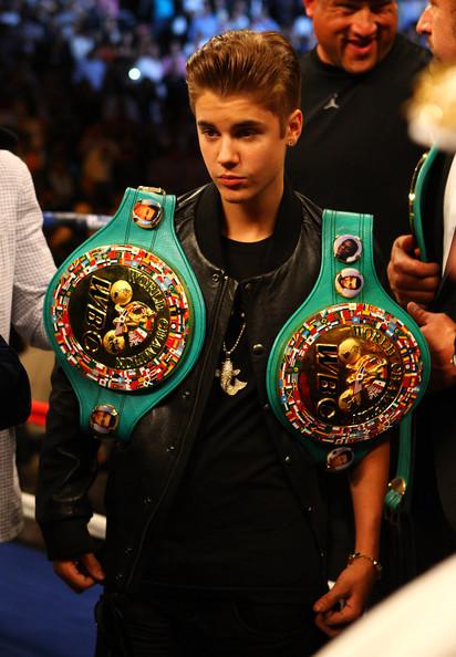 Justiin Bieber wearing two title belts at Miguel Cotto fight along with a Golden Koi Fish necklace worth $20,000.