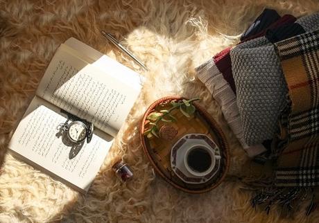 A book, a cup of coffee, and a few pieces of clothes on the shaggy rug.