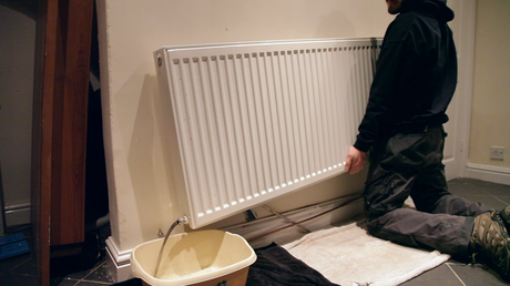 Man pouring water from a radiator into a washing up bowl