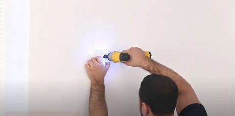 man fixing radiator brackets to a wall with a drill