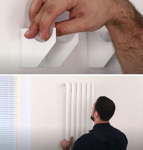 man hanging a vertical radiator on a wall